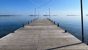 A wooden pier extending into calm water with a clear sky above. - kai urla (Urla)