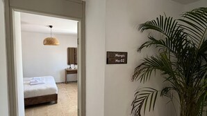 A hotel room with a bed, a bedside table, a hanging light fixture, and a potted plant. - kai urla (Urla)