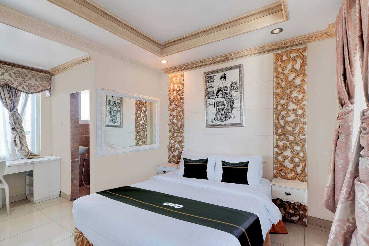 A hotel room with a large bed, a desk, and a shower area.