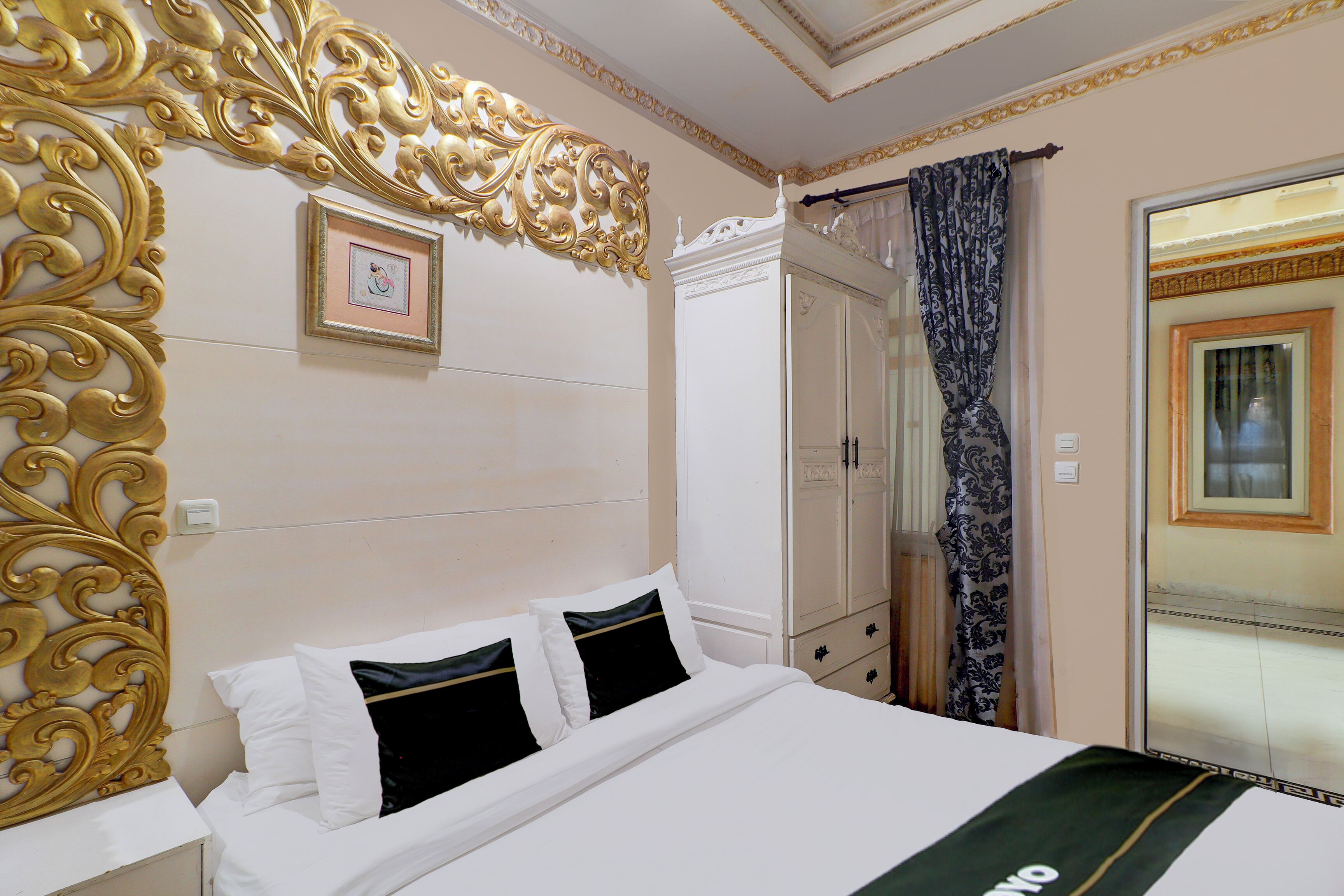 A hotel room with a large bed, a wardrobe, and a mirror with a curtain.
