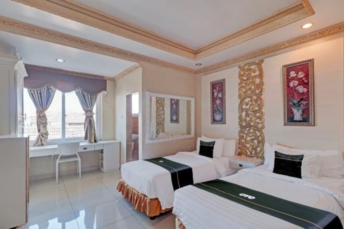 Habitación de hotel con dos camas, un escritorio y una silla.