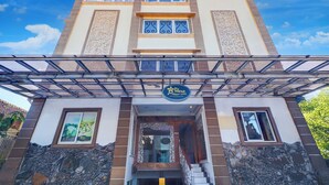 A hotel entrance with a covered walkway, a signboard, and a stone facade. - Hotel O My Home@Bali (Kuta)