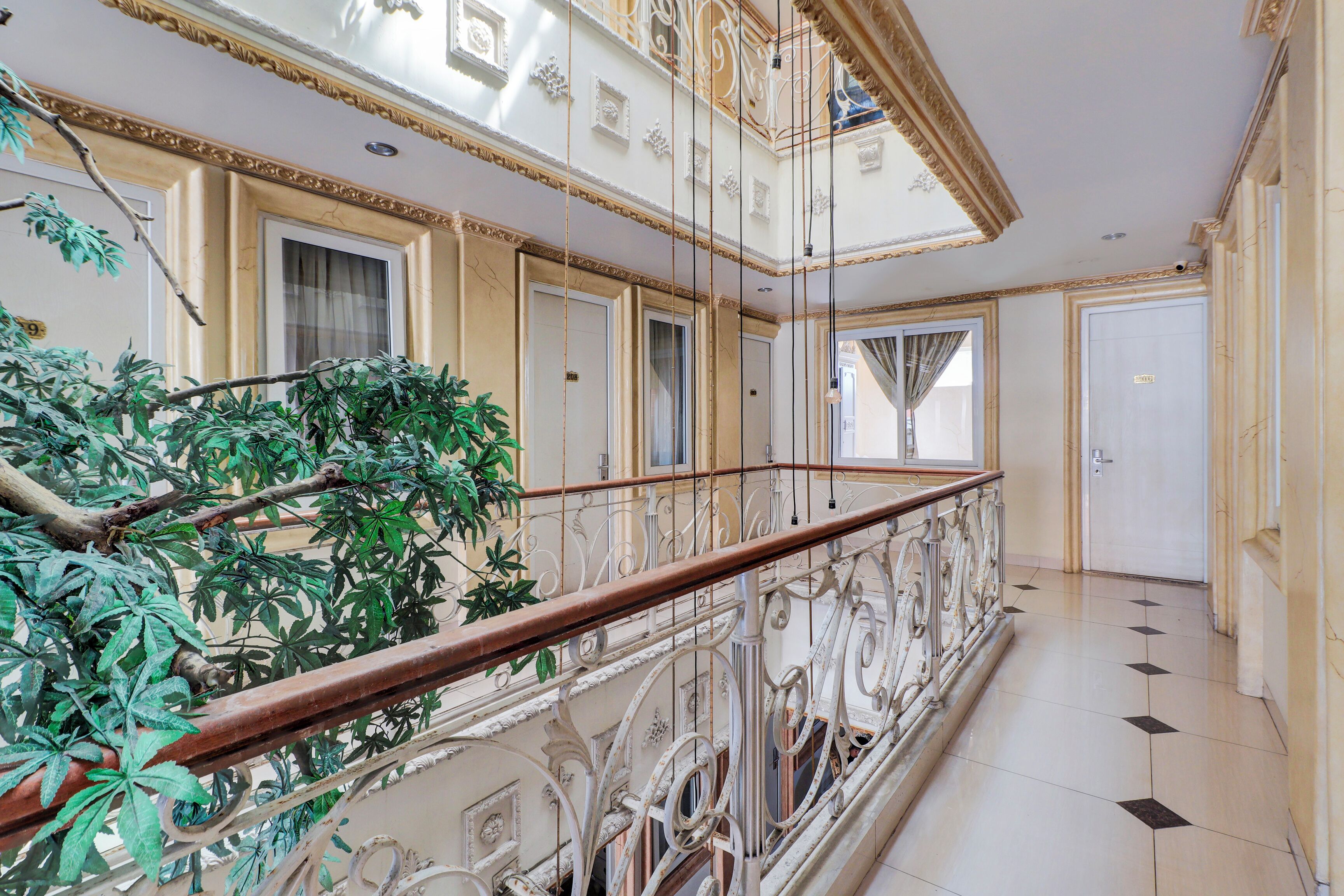 A grand interior with ornate railings, a staircase, and a large potted plant.