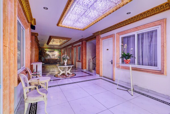 A hallway with marble flooring, a chandelier, and a potted plant. - Hotel O My Home@Bali (Kuta)