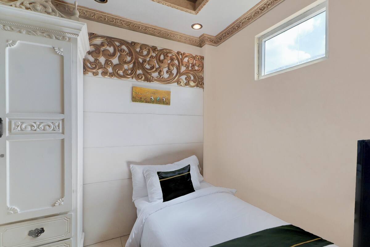 A bedroom with a bed, a dresser, a decorative wall panel, and a window.