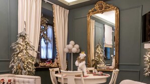 Ein gemütliches Zimmer mit einem großen Spiegel, einem Weihnachtsbaum und einem Esstisch mit Stühlen.
