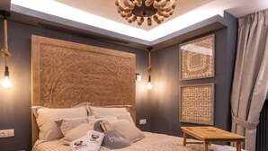 Ein Schlafzimmer mit einem großen Bett, einem hölzernen Kopfteil, einer Chandelüster und Wandbildern.