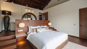 Ein modernes Schlafzimmer mit einem Holzkopfteil, einem großen Spiegel und einer eingebauten Sitzbank am Fußende des Bettes.
