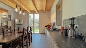 A modern kitchen with wooden beams, a dining area with a table and chairs, and a view of greenery outside. - Elegant Villa with Garden - Perfect for Groups (Potenza Picena)