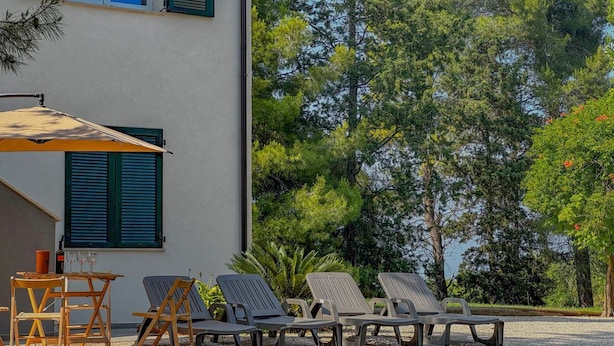A patio with outdoor furniture, a table with glasses, and a building with shutters. - Elegant Villa with Garden - Perfect for Groups (Potenza Picena)