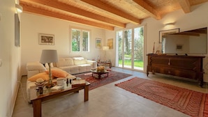 A spacious living room with a wooden ceiling, a sofa, a coffee table, and a fireplace. - Elegant Villa with Garden - Perfect for Groups (Potenza Picena)