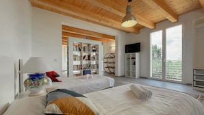 A bedroom with two beds, a bookshelf, a TV, and a large window. - Elegant Villa with Garden - Perfect for Groups (Potenza Picena)