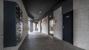 A corridor with a tiled floor, a metal gate on the left, and a door on the right. - Apartamenty Sun & Snow Zamoyskiego (Warsaw)