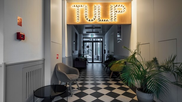 A hotel lobby with a checkered floor, a reception desk, and a sign that reads "TULP". - Apartamenty Sun & Snow Zamoyskiego (Warsaw)