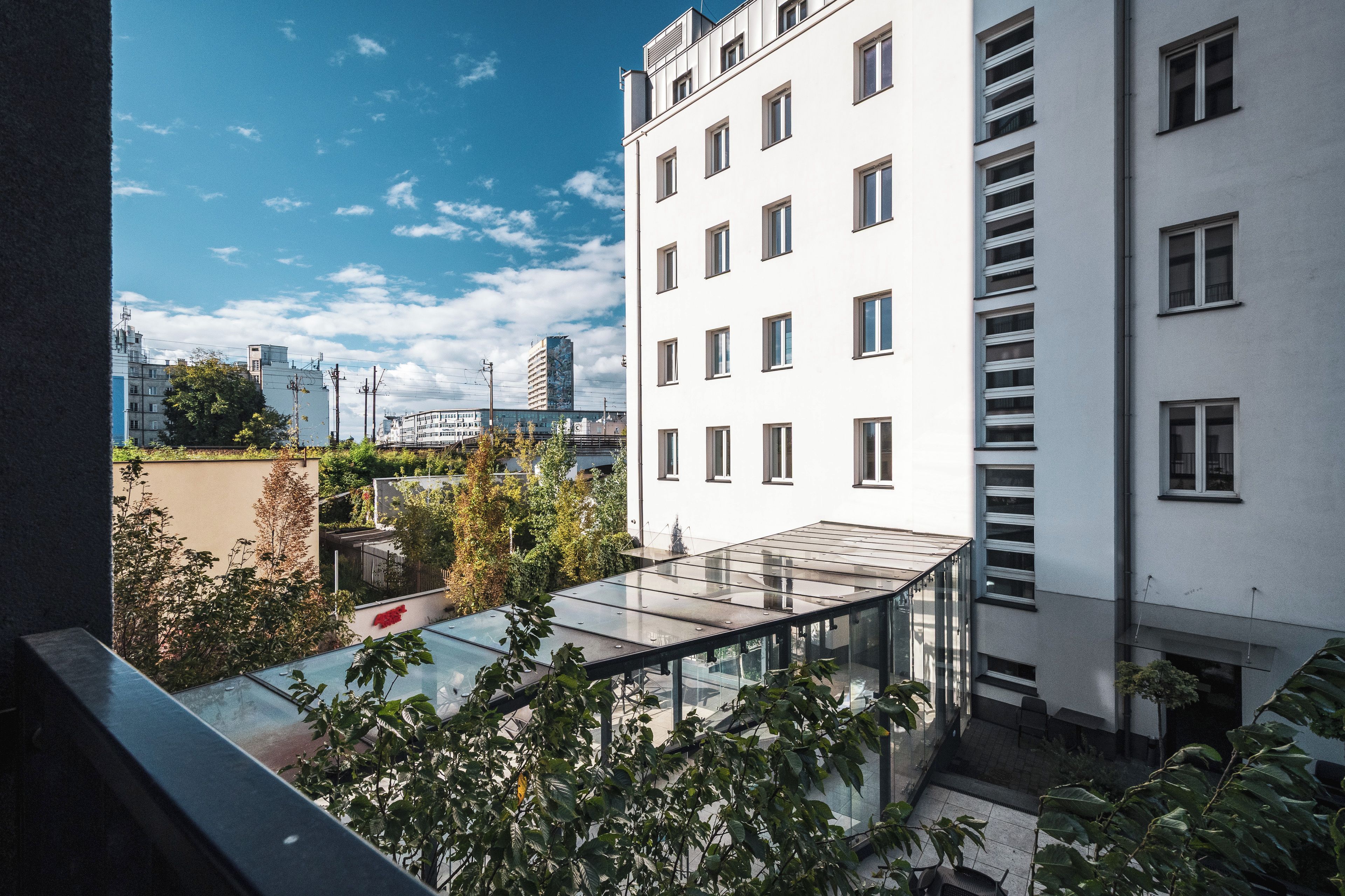 Un bâtiment moderne doté d’une véranda en verre et offrant une vue sur le paysage urbain.