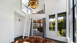 A spacious room with a large window, a staircase, and a view of the outdoors. - Arrowtown Luxury Escape with Hot Tub & BBQ (Arrowtown)