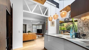 A modern kitchen with white cabinetry, a central island, and pendant lighting. - Arrowtown Luxury Escape with Hot Tub & BBQ (Arrowtown)