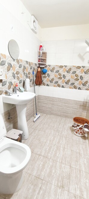 Bathroom features a pedestal sink, toilet, bidet, and leaf-patterned tile design.