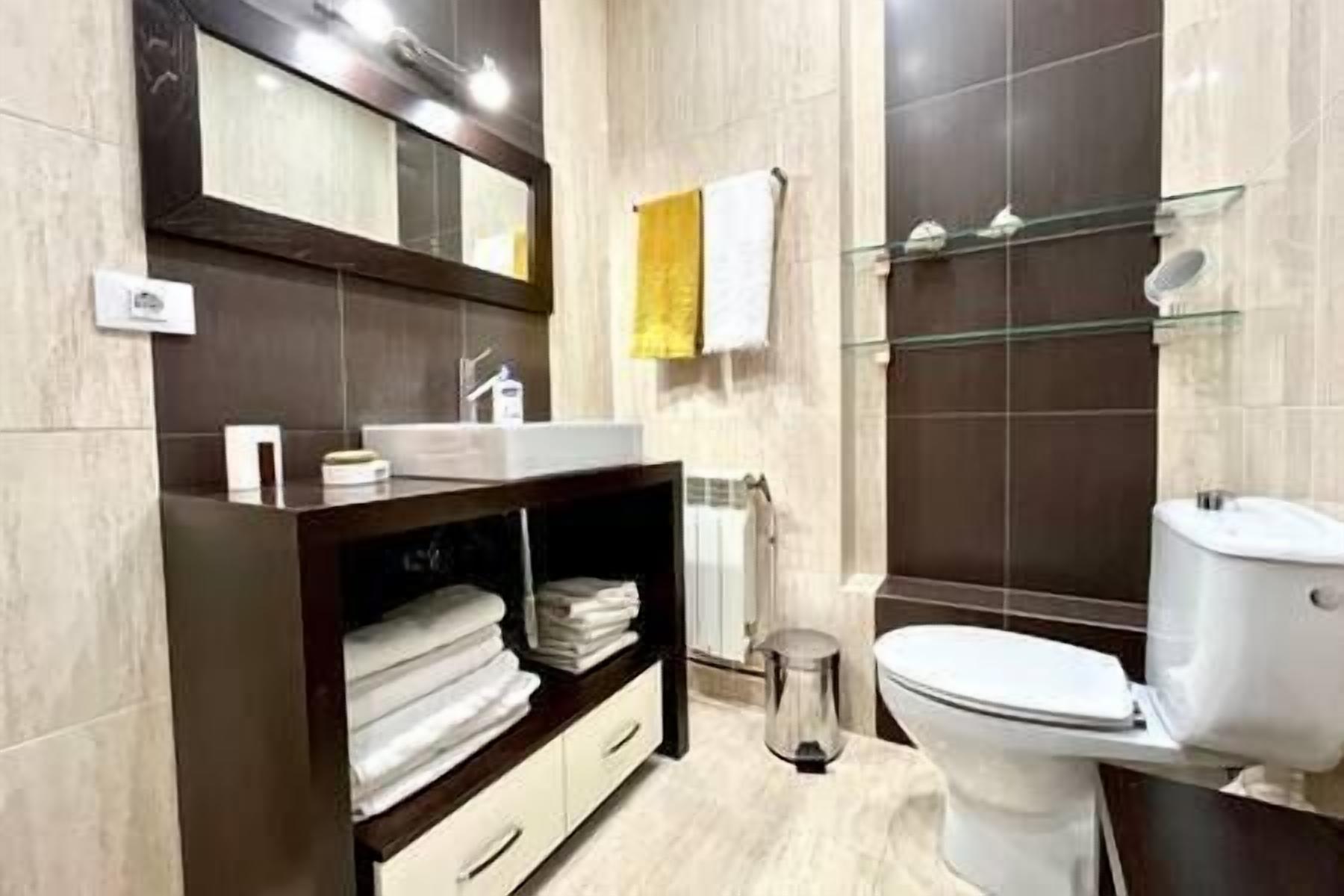 A modern bathroom with a dark wooden vanity, a white sink, and a glass shower enclosure.