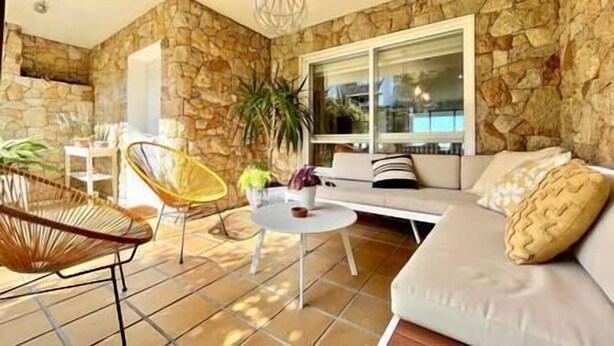 A cozy living area with a stone wall, a white sofa, a yellow chair, and a small round table. - Villa in Baiona YBH (Baiona)