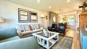 A living room with a sofa, a coffee table, and a dining area with chairs. - Villa in Baiona YBH (Baiona)