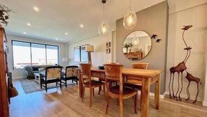 A dining area with a wooden table and chairs, a rug, and a wall-mounted mirror. - Villa in Baiona YBH (Baiona)