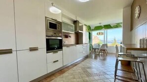A modern kitchen with white cabinets, stainless steel appliances, and a dining area with a view. - Villa in Baiona YBH (Baiona)