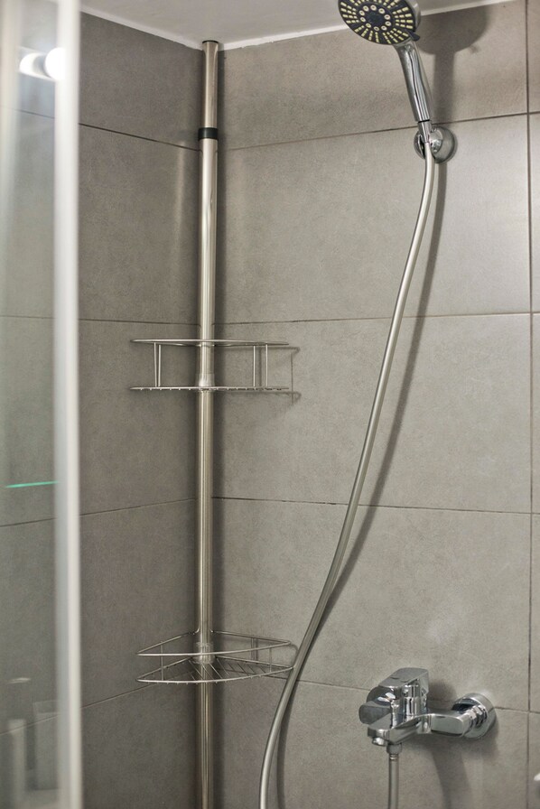 Ducha con cabezal de ducha manual, barra vertical cromada y grifo empotrado en la pared.