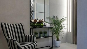 Un interior moderno con un sillón a rayas, un espejo alto y una planta en maceta.