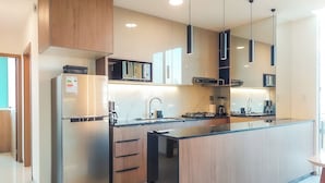Una cocina moderna con refrigerador de acero inoxidable, microondas, estufa y armarios de madera.