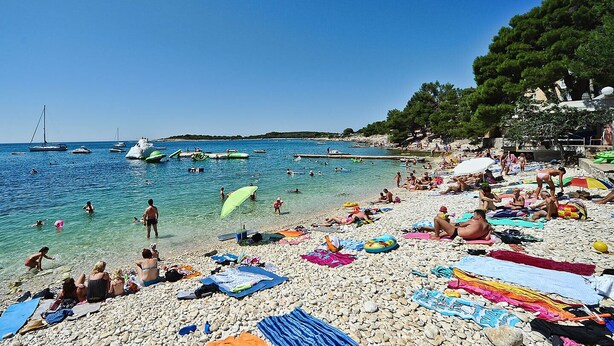 A crowded beach with people sunbathing and swimming, surrounded by boats and a rocky shoreline. - 3-bedroom apartment in village Vinkuran (Vinkuran)