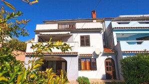 A two-story building with a white facade, a balcony on the upper floor, and a satellite dish on the side. - 3-bedroom apartment in village Vinkuran (Vinkuran)