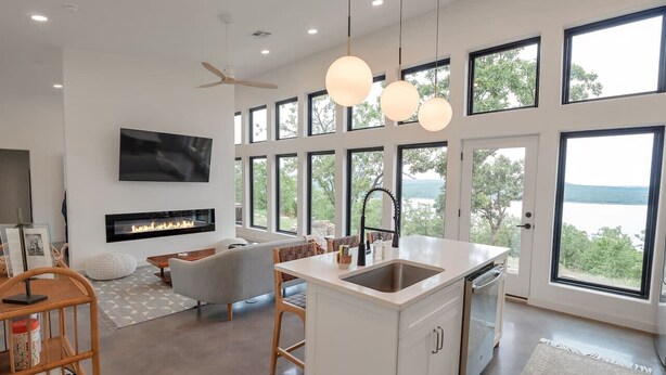 Een moderne keuken met een centraal eiland, grote ramen en een open haard.