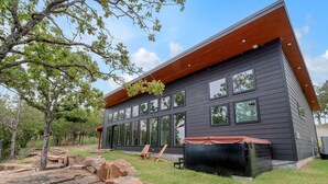 Een modern huis met twee verdiepingen, een donkere gevel, grote ramen en een houten dak.