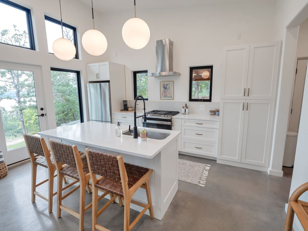Una cucina moderna con isola centrale, mobili bianchi e luci a sospensione.