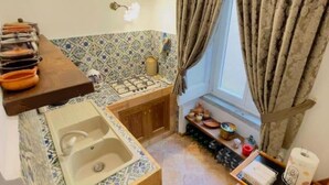 A compact kitchen with a sink, stove, and a window with curtains.