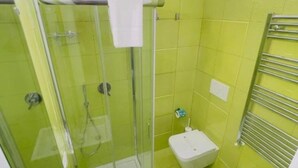 A bathroom with a glass-enclosed shower, a white toilet, and a chrome towel rack.