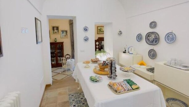 A dining area with a table set for a meal, a white ceiling, and decorative plates on the wall.