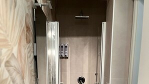 Une salle de bain moderne avec une douche, un lavabo et un miroir.