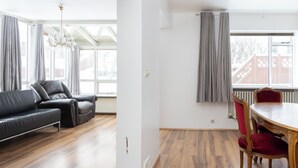 A living room with a leather sofa, a dining table with chairs, and a chandelier. - Summerday Guesthouse (Reykjavík)