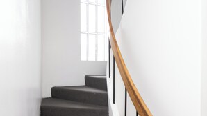 A staircase with a wooden handrail and a window at the top. - Summerday Guesthouse (Reykjavík)