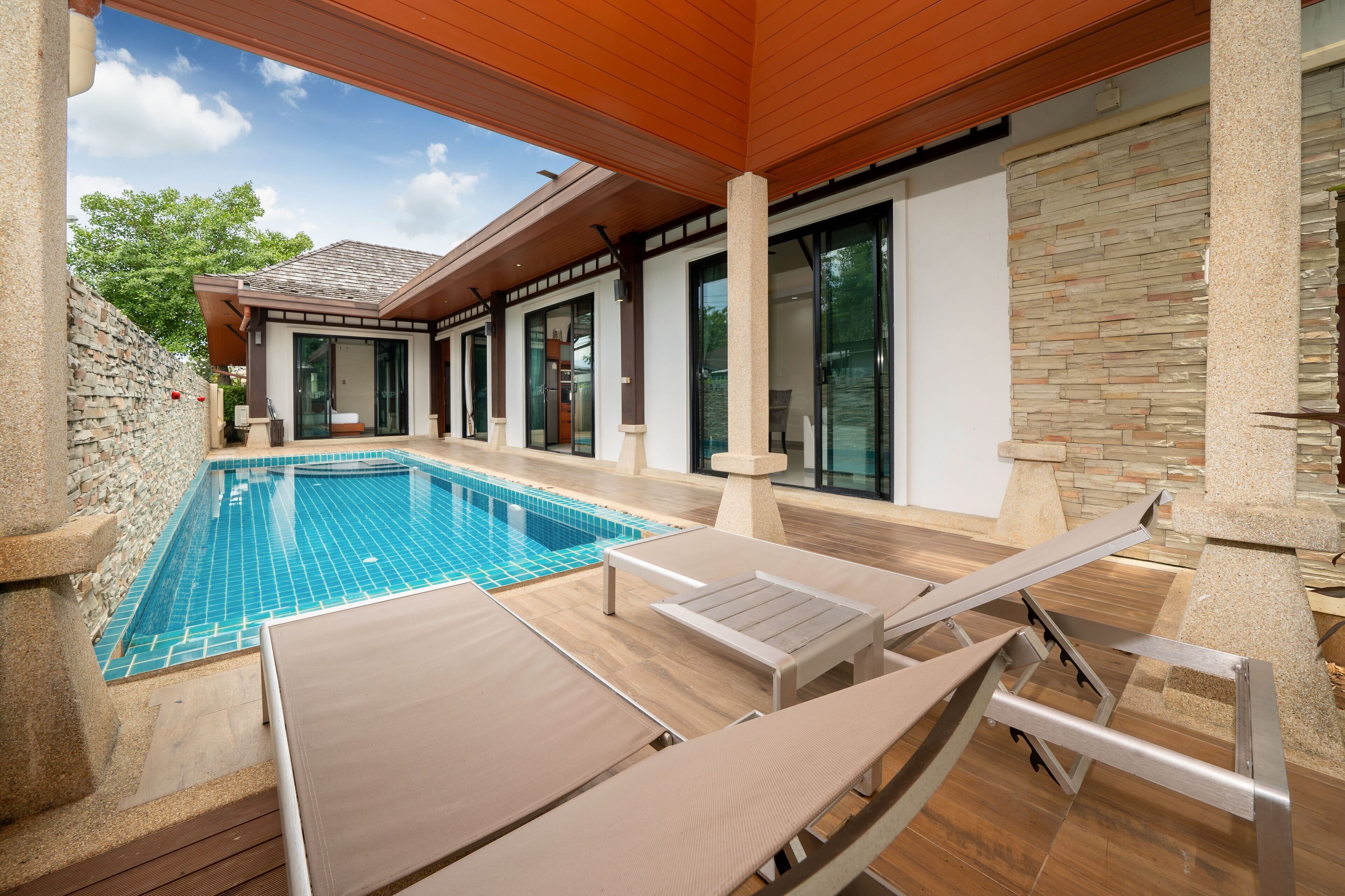 Een buitenzwembad, ligstoelen bij het zwembad