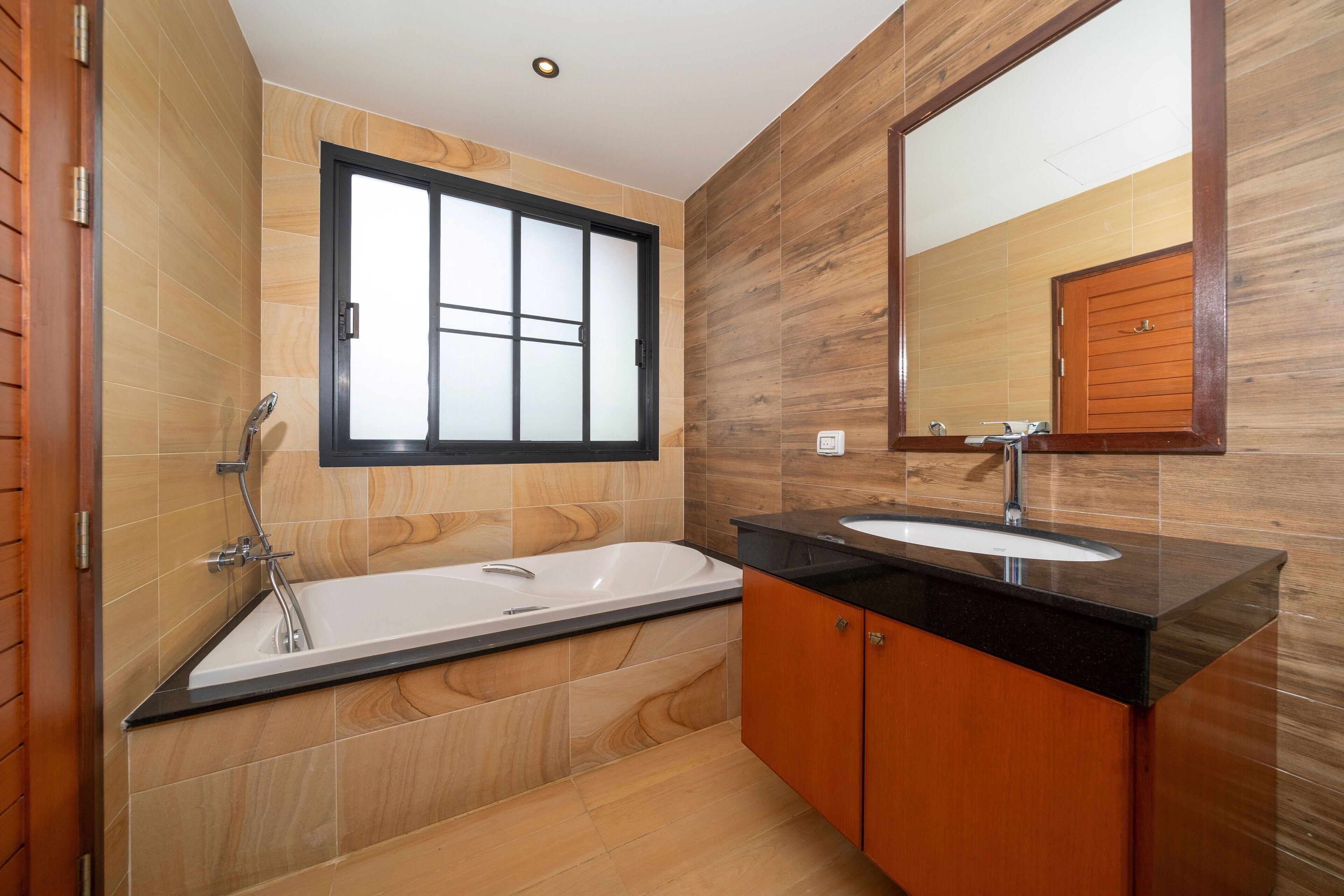 Un baño moderno con bañera, lavamanos y un espejo grande.