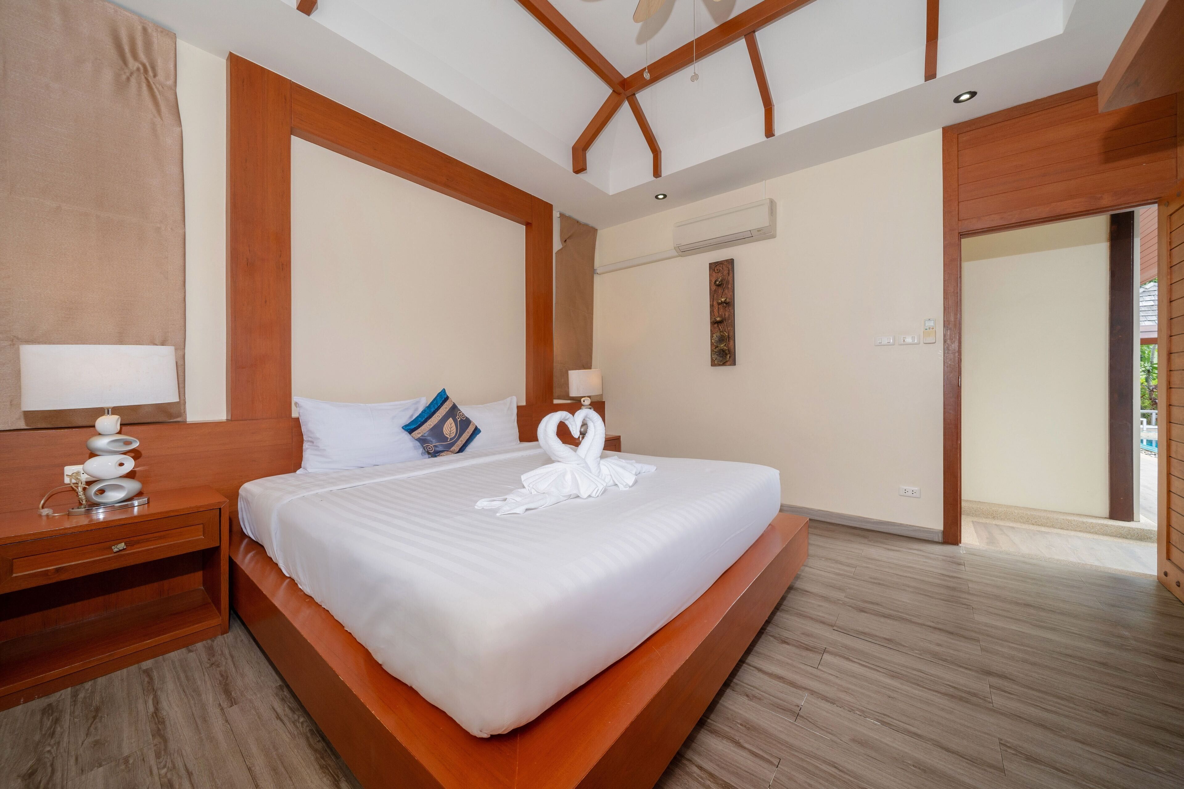 A hotel room with a large bed, wooden headboard, bedside tables, and a view of the outside.