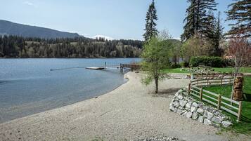 Enjoy a serene lakeside view with a clear view of the water, a dock, and a pathway leading to a fenced area with a statue.