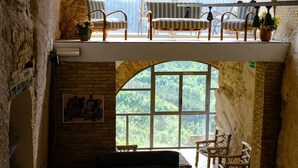 A spacious loft with a high ceiling, a cozy seating area with a sofa and chairs, a chess table, and a large arched window offering a view of the landscape. - Il castello di atessa  (Atessa)