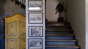 A staircase with four framed black and white photographs on the wall, a yellow cabinet with decorative patterns, and a potted plant on the right. - Il castello di atessa  (Atessa)