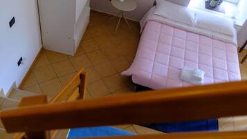 A bedroom with a bed, a small table, and a chair.