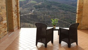 A balcony with two wicker chairs and a small table, overlooking a valley with a road and hills. - Il castello di atessa  (Atessa)