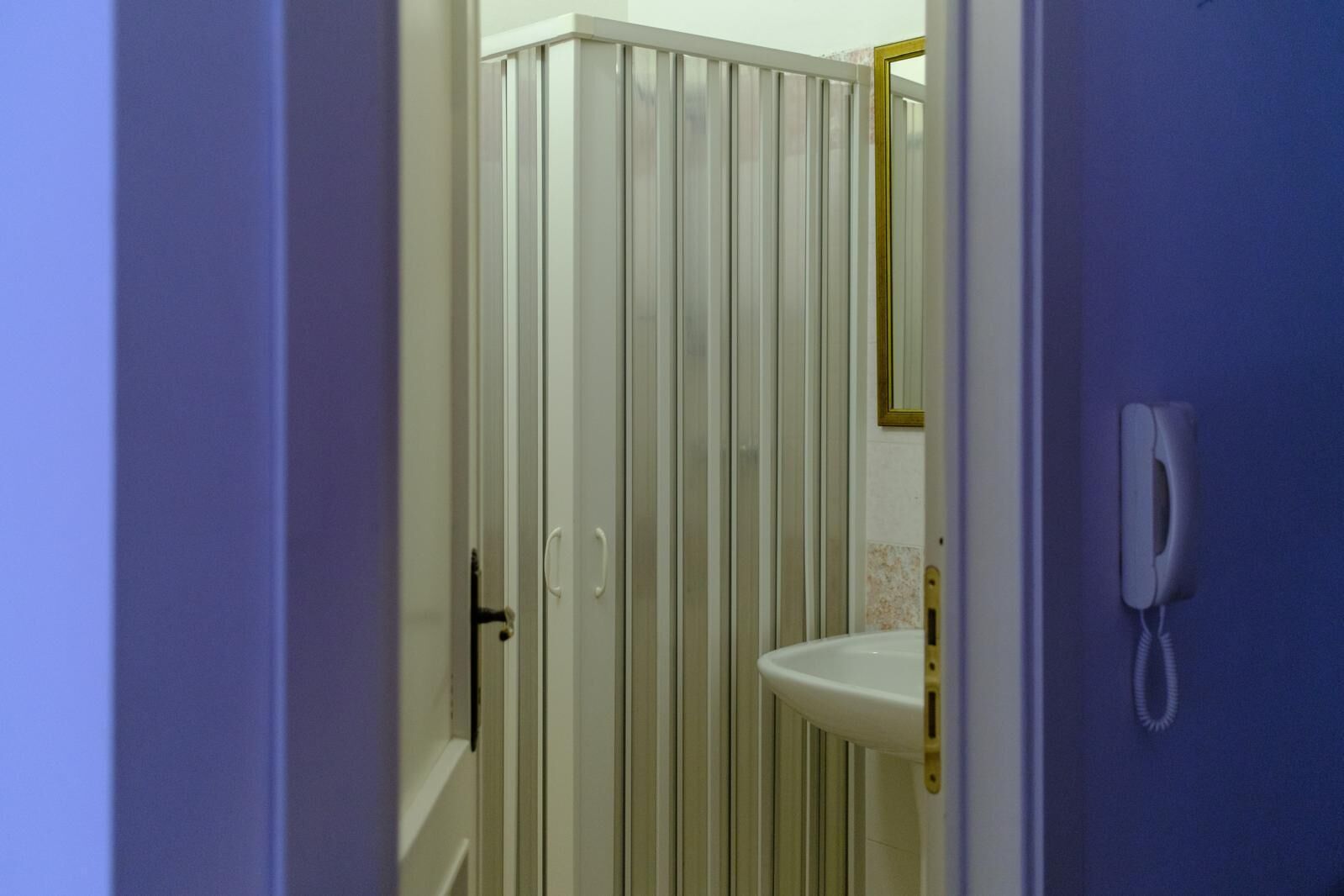 Ein Badezimmer mit einem weißen Waschbecken, einem Spiegel und einem Telefon.